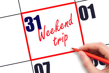 31 st day of the month. Hand writing Weekend trip reminder and drawing red frame on calendar with red pen on white background. Business concept. Travel concept. Planning and scheduling.