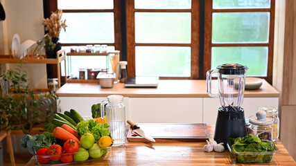 Fresh vegetables and fruits arranged on a wooden kitchen counter with a blender, ready for meal preparation