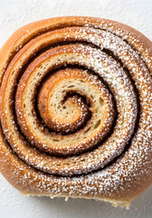 Fototapeta premium Warm, delicious cinnamon roll sprinkled with powdered sugar, perfect for breakfast or a sweet treat, inviting indulgence and comfort food vibes