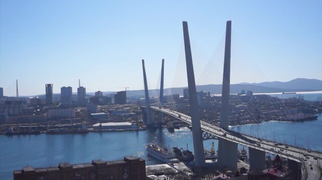 Zolotoy Bridge spanning Golden Horn Bay in Vladivostok, Russia, modern city skyline and waterfront with hills, bright spring daylight.
