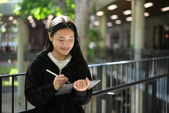 Teen girl using a digital tablet with stylus in an open school environment - Powered by Adobe