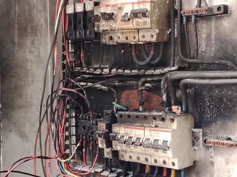 Burned and damaged industrial electrical control panel interior, indicating equipment failure and fire risk.