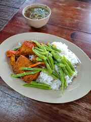 Healthy Vietnamese vegetarian food served with rice, tofu, soy meat and green beans on a plate. Traditional Asian meal on a wooden table.