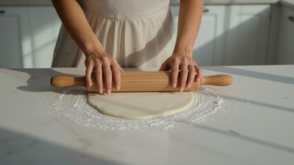 Woman's hand using a wooden rolling pin to flatten the dough