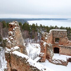 Fototapeta premium Ruined medieval structure overlooking winter landscape with frozen lake