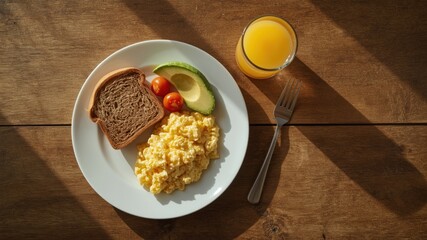 healthy breakfast of toast with avocado, scrambled eggs and a glass of orange juice