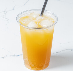 A tall cup of iced tea glistens with ice cubes, reflecting colors on a smooth marble table