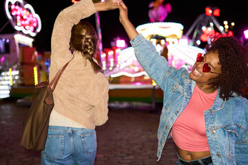 Diverse young women enjoying carnival activities at night
