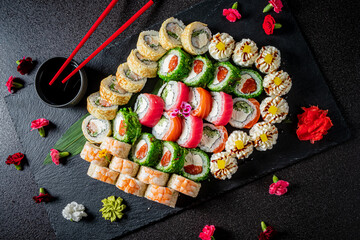 A vibrant sushi platter displays various rolls and garnishes on a dark background, inviting taste