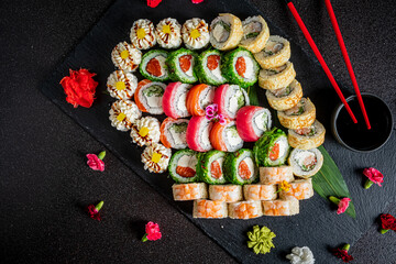 Vibrant sushi rolls artfully displayed on a dark background with flowers