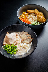 Two vibrant bowls of steaming noodles, chicken, and fresh veggies offer a cozy dining vibe