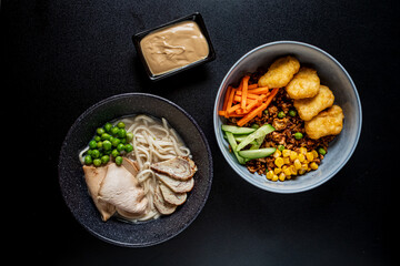 Two bowls of noodles, chicken, and colorful veggies make for a delightful meal