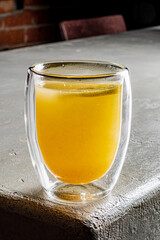 A warm drink in a clear cup glows softly on a textured surface, radiating comfort