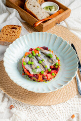 Vibrant layers of vegetables topped with fish and garnished with peas served alongside rustic bread