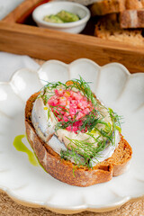 A delightful open sandwich features herring, colorful toppings, and drizzled olive oil