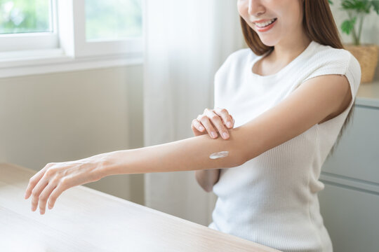Health skin care, beauty asian young woman, girl hand applying, putting moisturizer on her arm, elbow after shower bath in room at home. Skin body cream moisturizing lotion, routine in morning. - Powered by Adobe