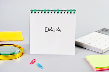 DATA word written in a notebook in a composition with a calculator, a magnifying glass, and stickers. Business strategy success concept