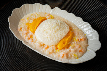 Creamy rice topped with a poached egg and fresh mango, served in an elegant bowl