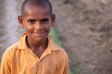 rural boy smiling near irrigation canal in village field, simple countryside portrait