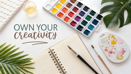 Inspirational workspace with watercolor palette, notebook, brushes, and plant showcasing creativity and artistic expression