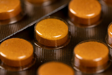 orange tablets in a blister , whole orange tablets packed in a metal-plastic blister closeup