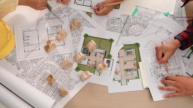 Architect and safety engineer discussion about building construction use blueprint on table with architectural document, measurement tool and wooden block scatter around at modern office. Delineation.