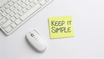 White Computer Mouse and Keyboard with a Yellow Sticky Note that Says Keep It Simple on a Light Background