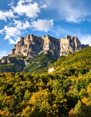 Majestic mountain rising above vibrant autumnal forest, clear sky