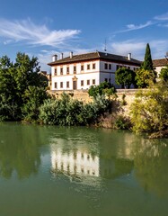 Fototapeta premium A stately white building beside a river, reflected perfectly