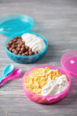 School breakfast lunch box. Chocolate and Cornflakes with yoghurt in a plastic container.