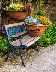Park bench with vibrant flower pots in a lush garden setting