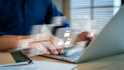 ERP document management concept. Businessman working on laptop computer with icons on virtual screen.