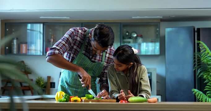 Indian father and daughter Chopping capsicum together, bonding in modern kitchen, Asian dad teaching young girl cooking, family quality time at home, child helping parent with meal preparation