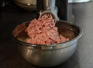 Electric meat grinder. Kitchen tool to mince meat. Meat grinding, preparing food ingredients. Modern meat grinder products on  table in kitchen. The process of cooking minced using an grinder. 