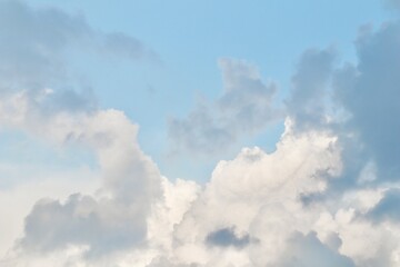 A mix of dark grey storm clouds and bright white cumulus formations against a pale blue sky, showing the transition of weather and dramatic atmospheric contrast.