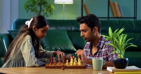 Playing chess together, Indian father and daughter sitting at table at home, Asian dad bonding with young girl over board game, family quality time, learning strategy, concentration, and fun - Powered by Adobe