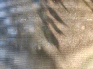 Natural background, shadows, and sunlight on a bus stop roof. Faint shadows cast on a ridged, textured surface create a calm, abstract pattern.