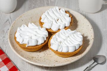Cream-filled cakes on a light wooden table