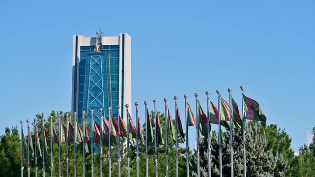 Waving Turkmenistan flags with the oil and gas university building in the background in Ashgabat