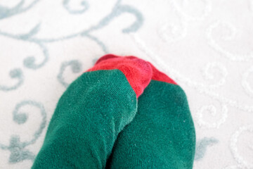 Green and red socks on the carpet. Men's feet wearing socks with New Year's colors theme. Top view, above, up. 