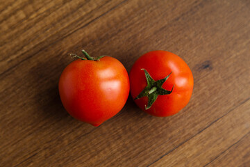 Fresh, tasty organic vegetables, two red tomato, isolated on brown wood cutting board