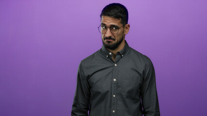 Young man with glasses standing against purple background showcasing a confident expression