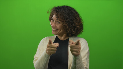Middle-aged hispanic woman points index fingers directly at camera in studio green screen; encouragement.