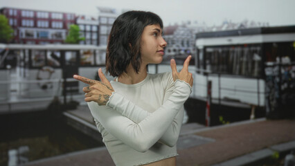 Young hispanic woman with brown hair and facial freckles points tattooed finger on busy street...