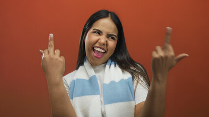 Confident woman flips her finger in a bold gesture on a red stage, portraying a young latin...