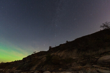 A magical night sky with countless stars and a green aurora borealis over the dramatic limestone...