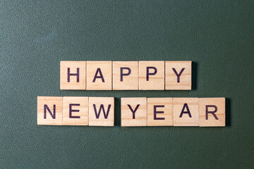 Wooden letter tiles spelling Happy New Year arranged neatly on a textured green background