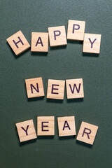 Wooden letter tiles spelling Happy New Year arranged neatly on a textured green background