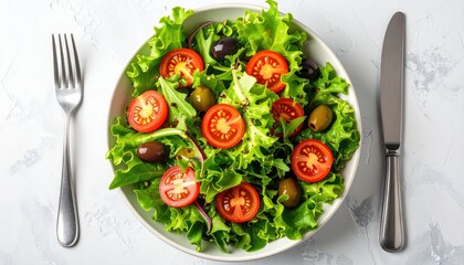 Fresh Salad with Lettuce Tomatoes Olives Quinoa in White Bowl on Gray Surface with Silver Fork and Knife Healthy Vegetarian Meal