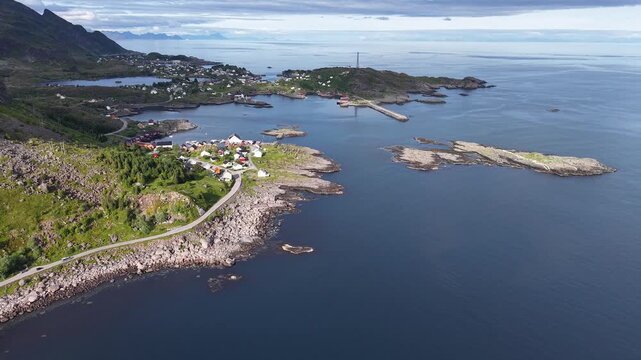 Scenic aerial shot following a road by the coast, revealing vibrant green shores, crystal blue waters, and picturesque islands under a clear sky